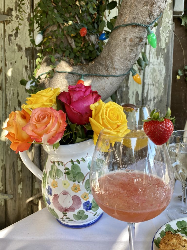 Hand painted pitcher with roses, strawberry mimosa, christmas lights, alfresco brunch