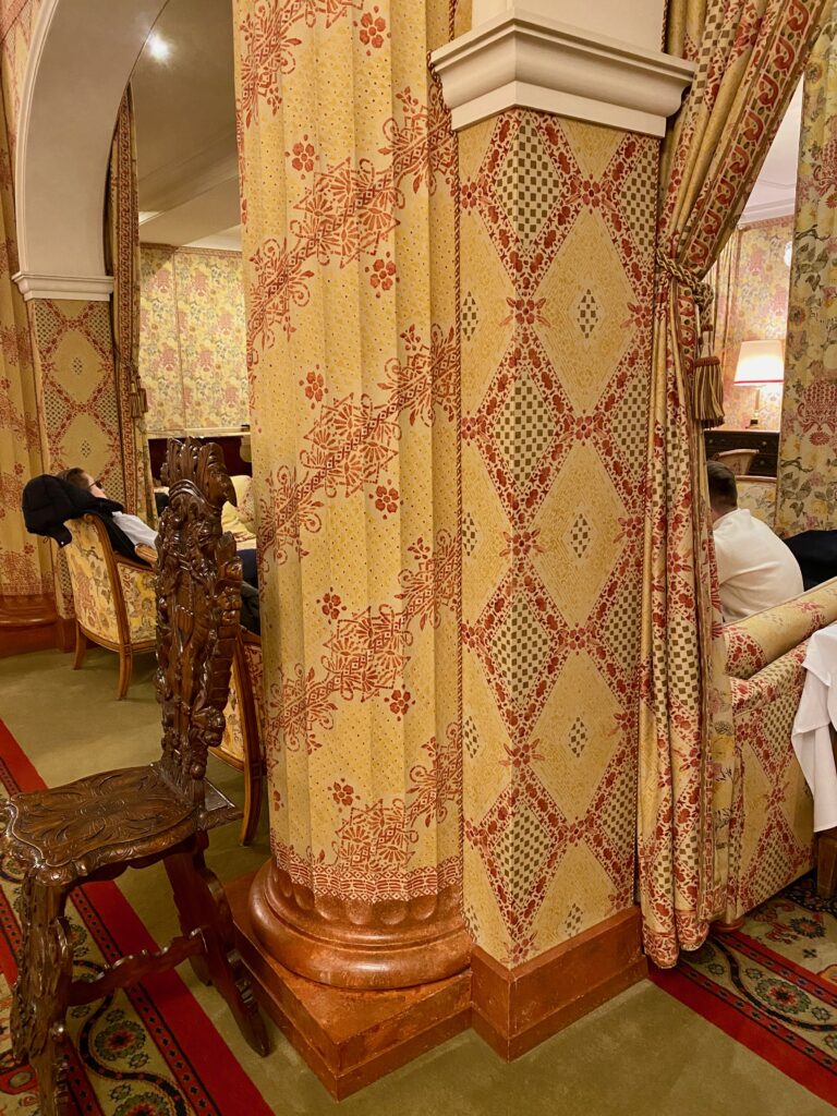 Hotel Kulm, St. Moritz, large fireplace mantel, gold and ruby wallpaper, gold and ruby upholstery, gold and ruby curtains