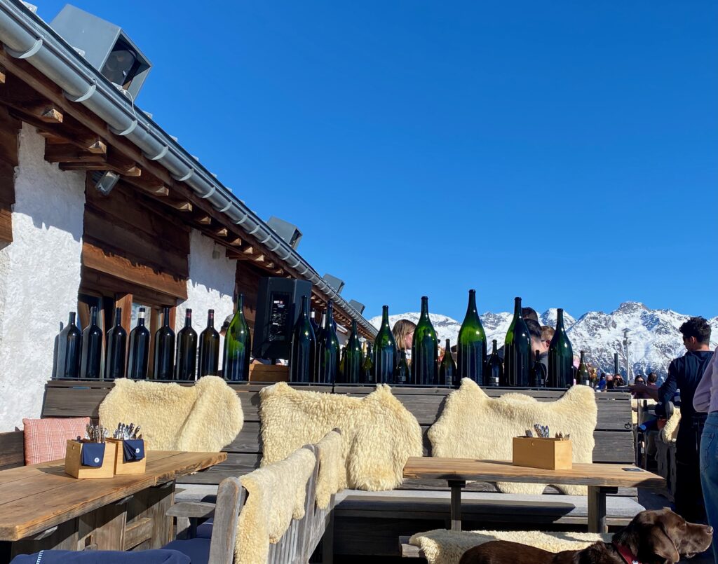 Paradiso club, Saint Moritz, après ski, shearling seat covers, The alps, elegant food in a rustic setting, alfresco dining, indoor outdoor living, wine bottles, large format wine bottles