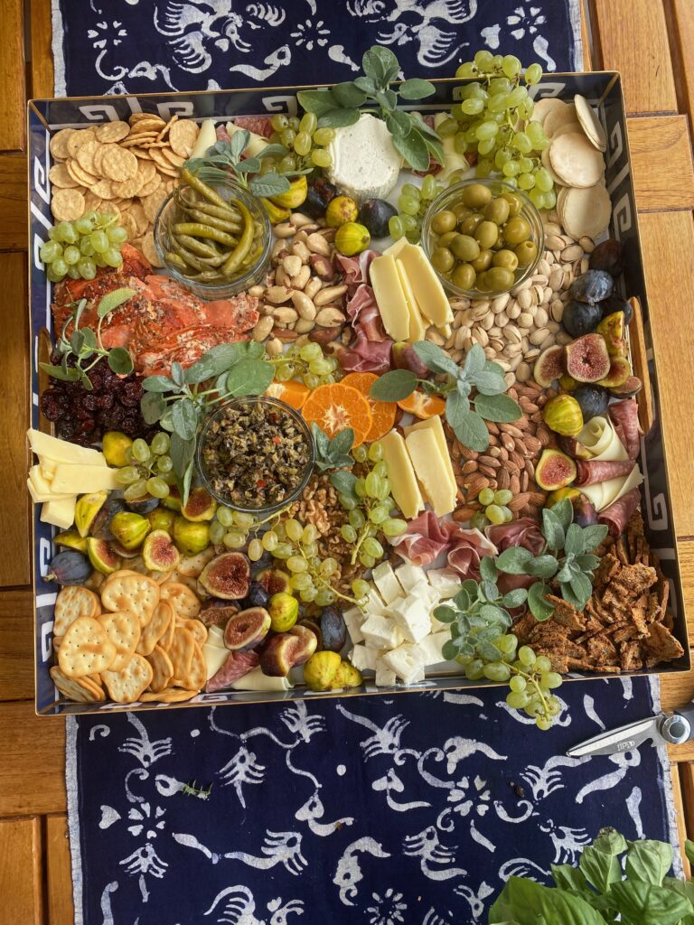 Splendid Party platter, crackers, pistachio nuts, dried sour cherries, blue and white tray, pickled peppers, olives, splendid fêtes, splendid food, Brazil nuts, cut oranges, Boursin cheese, tapenade, cheese slices, sage sprigs, grapes, green grapes