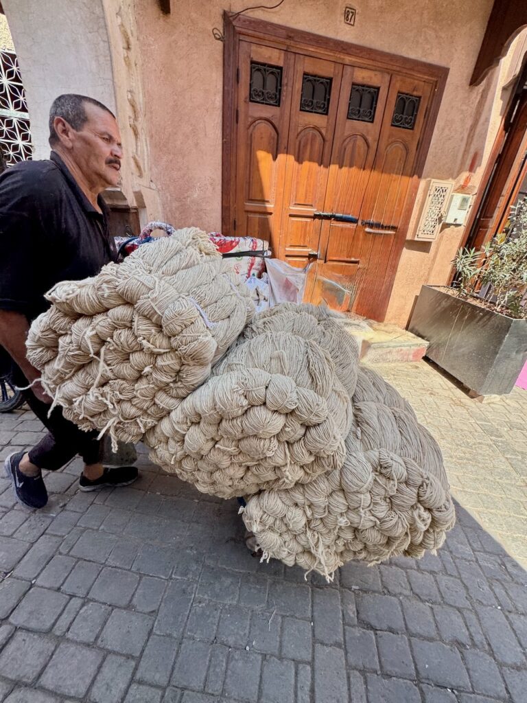 Souk, Marrakech, Medina, skeins of wool, man pushing cart
